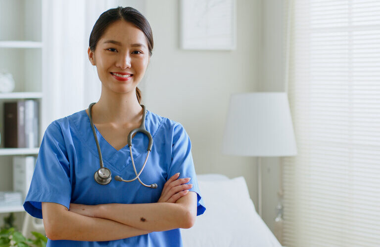PortrÃ¤t einer jungen asiatischen Krankenschwester, die in die Kamera lÃ¤chelt.