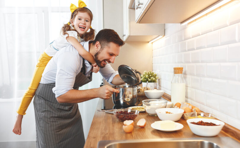 glückliche Familie in der Küche. Vater und Kind Tochter kneten Teig und backen die Kekse zusammen